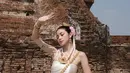 Regina juga berpose dengan gaya tarian khas Thailand, berlatar belakang reruntuhan kuil kuno yang memberikan nuansa budaya yang kental. Dengan sinar matahari yang terang, suasana menjadi semakin autentik, menciptakan keindahan warisan Thailand yang tak tertandingi. Penampilan Regina dalam balutan Chut Thai semakin menguatkan kesan bahwa ia adalah sosok yang menghargai budaya. (Liputan6.com/IG/@reginaaphx)