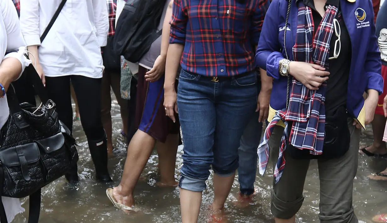 Cathy Sharon bersama Heppy Farida melitasi genangan air saat meninjau lokasi banjir di Pancoran, Jakarta, Selasa (21/02). Selain meninjau lokasi Cathy Sharon dan Heppy Farida juga memberikan bantuan untuk warga setempat. (Liputan6.com/Herman Zakharia)