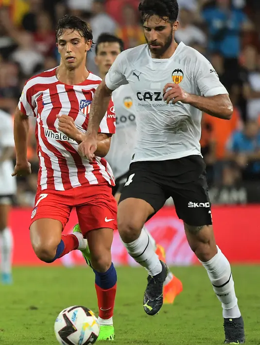 Penyerang  Atletico Madrid, Joao Felix (kiri) membawa bola dari kejaran bek Valencia, Eray Comert dalam pertandingan lanjutan La Liga Spanyol di stadion Mestalla di Valencia (30/8/2022). Atletico Madrid menang tipis atas tuan rumah Valencia 1-0. (AFP/Jose Jordan)