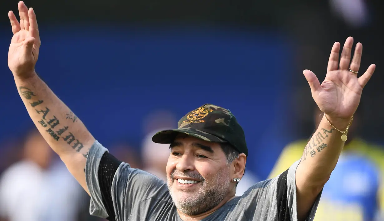 Legenda sepak bola, Diego Maradona, menyapa anak-anak sebelum memberikan pelatihan di Barasat, Selasa (12/12/2017). Kunjungan ini dilakukan pria asal Argentina itu dalam rangkaian liburan. (AFP/Dibyangshu Sarkar)