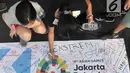 Pengunjung membubuhkan tanda tangan di atas spanduk raksasa saat car free day (CFD) di Bundaran HI, Jakarta, Minggu (22/7). Doa dan pengumpulan tanda tangan ini diinisiasi Komunikonten untuk mendukung atlet Asian Games 2018. (Merdeka.com/Iqbal Nugroho)