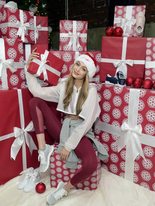 Gigi Hadid berpose di depan tumpukan kado dalam Holiday Party yang digelar Reebok di New York City, 14 Desember 2017. Gigi tampil sporty berbalut training suit serba merah yang memperlihatkan abs seksinya. (Jason Kempin/Getty Images for Reebok/AFP)