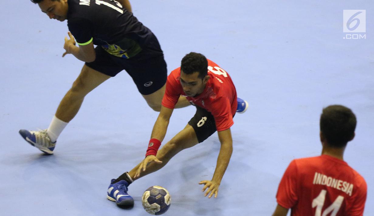 Pemain bola tangan Indonesia, Oni Arianus (kiri) berebut bola dengan pemain Malaysia pada penyisihan grup 3 bola tangan Asian Games 2018 di GOR PP POPKI, Jakarta, Minggu (26/8). Indonesia unggul 31-22. (Liputan6.com/Helmi Fithriansyah)