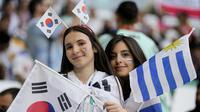 Suporter wanita Korea Selatan juga berbaur dengan suporter Uruguay. Itu terlihat saat keduanya berpose bersama sebelum laga dimulai. (AP Photo/Martin Meissner)
