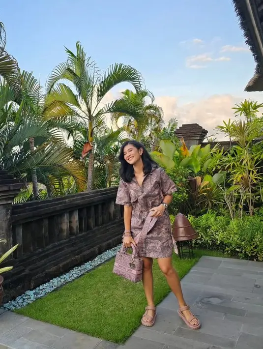Berada di Bali, Dian tampil dengan dress pink bermotif dari Dior yang serasi dengan tasnya. [@therealdisastr]