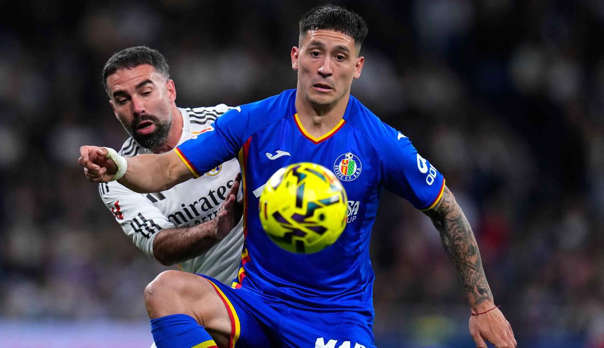 Kekalahan ini membuat Los Blancos gagal memangkas jarak dengan pimpinan klasemen La Liga, Barcelona. Tampak dalam foto, Martin Satriano dari Getafe (kanan) berebut bola dengan pemain Real Madrid, Dani Carvajal, saat pertandingan pekan ke-26 La Liga 2025/2026 di Stadion Bernabeu, Madrid, Spanyol, Senin 2 Maret 2026 waktu setempat atau Selasa (3/3/2026) dini hari WIB. (AP Photo/Manu Fernandez)
