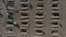 Aktivis LSM Rio de Paz menggali kuburan sebagai bentuk protes di pantai Copacabana, Rio de Janeiro, Kamis (11/6/2020). Kuburan-kuburan dengan simbol salib hitam yang dihiasi bendera Brasil kecil itu untuk mengenang puluhan ribu pasien corona yang meninggal di negara tersebut. (AP Photo/Leo Correa)