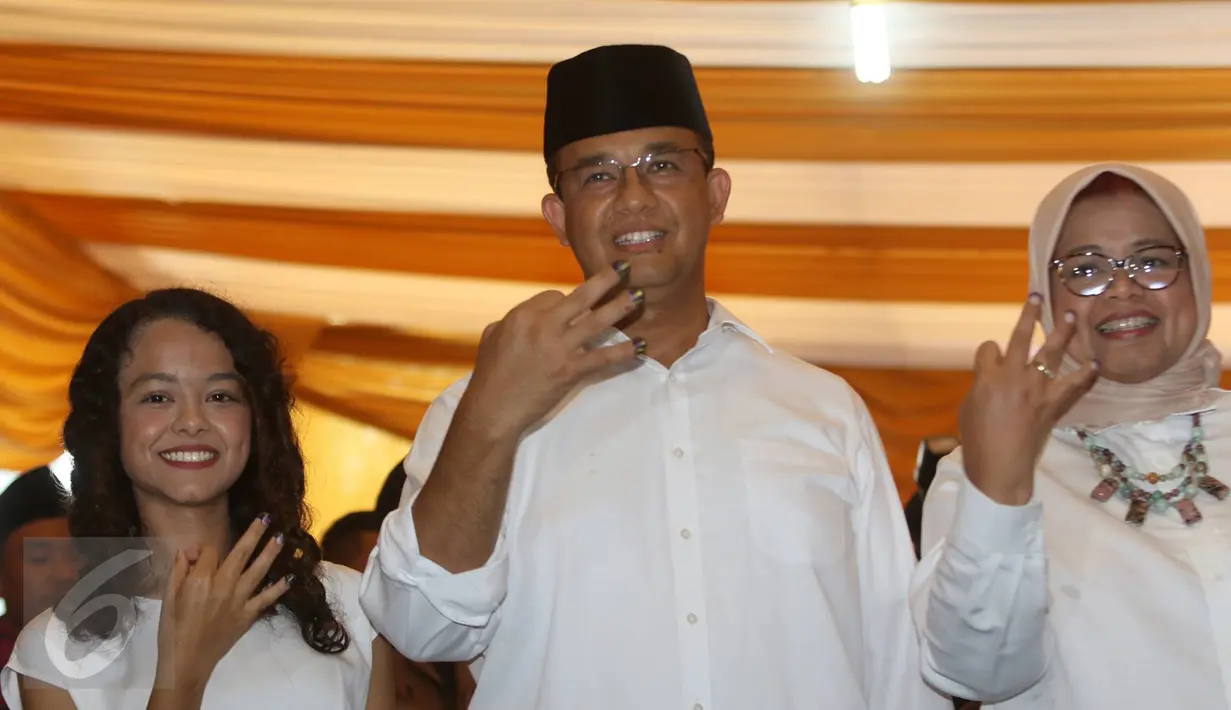 Calon Gubernur DKI Jakarta Anies Baswedan bersama istri, Fery Farhati, dan anak perempuannya menunjukkan jarinya yang telah dicelup tinta sambil berpose salam tiga jari di TPS 028 Cilandak Barat, Jakarta, Rabu (15/2). (Liputan6.com/Immanuel Antonius)