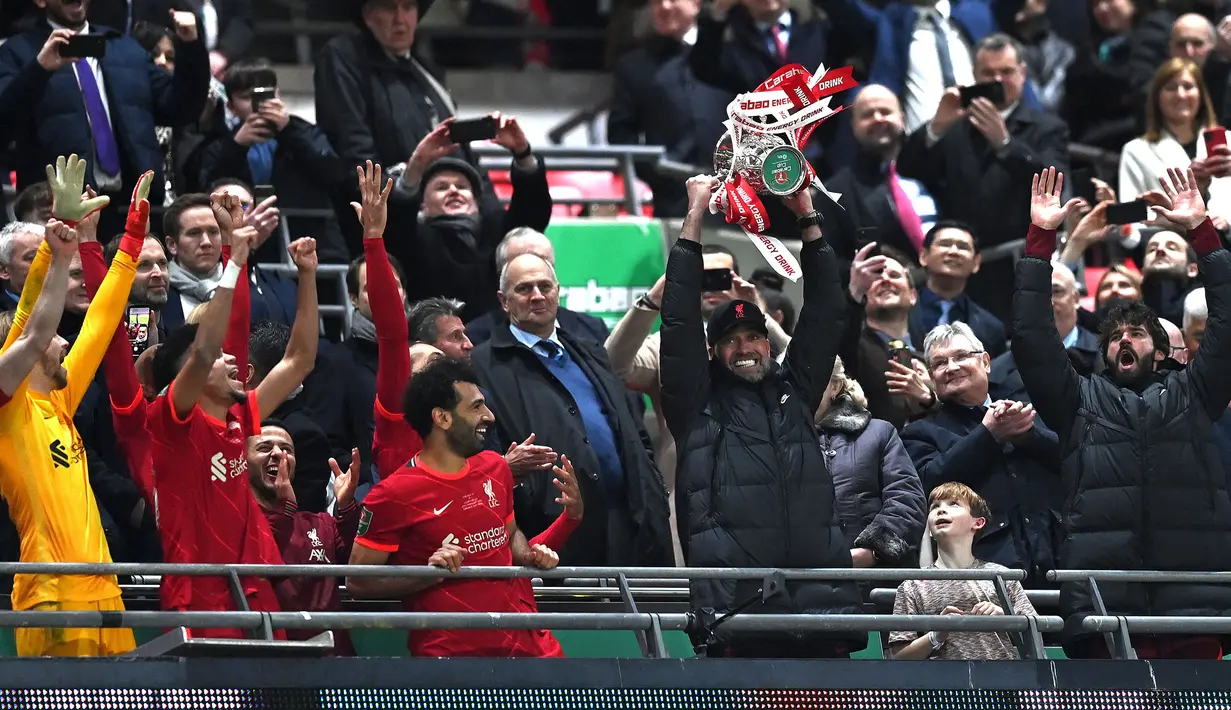 Pelatih Liverpool, Jurgen Klopp mengangkat trofi Carabao Cup 2021/2022 setelah mengelahkan Chelsea pada laga final yang berlangsung di Wembley Stadium, London, 27 Februari 2022. The Reds menang pada babak penalti dengan skor 11-10. Ini merupakan gelar Carabao Cup ke-9 bagi klub yang berkandang di Anfield tersebut. (AFP/Glyn Kirk)