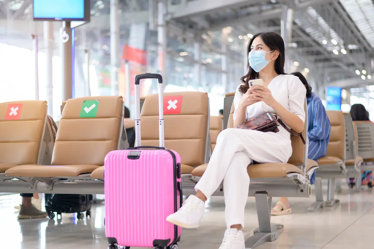 perempuan di bandara traveling memakai masker