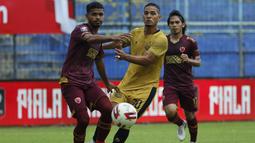 Pemain Bhayangkara Solo FC, Renan Da Silva (tengah) dijaga ketat pemain PSM Makassar, Hasim Kipuw (kiri)  dalam pertandingan matchday ke-2 Babak Penyisihan Grup B Piala Menpora 2021 di Stadion Kanjuruhan, Malang, Sabtu (27/3/2021). Kedua tim bermain imbang 1-1. (Bola.com/Ikhwan Yanuar)