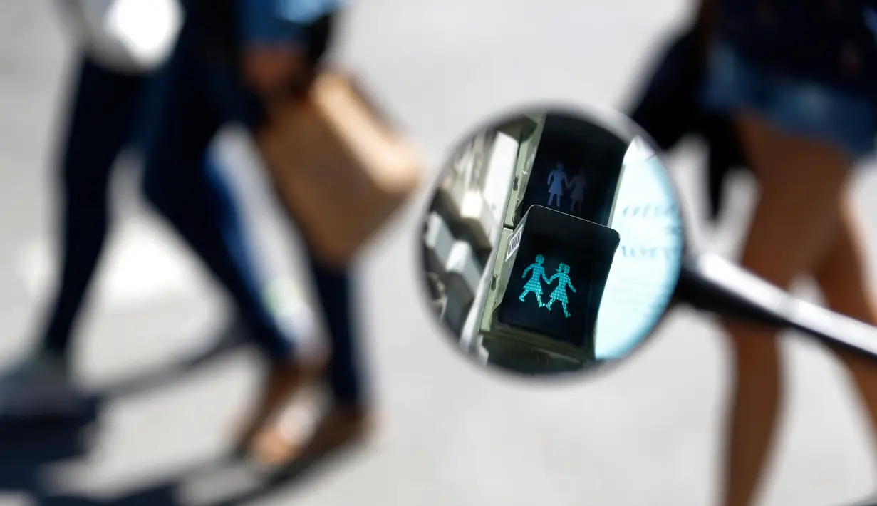 Pantulan lampu lalu lintas berlambang LGBT dari spion motor di Madrid, Spanyol, Selasa (6/6). Madrid memasang lampu lalu lintas khusus pasangan sesama jenis untuk menyambut Festival WorldPride yang akan digelar akhir bulan ini. (AP Photo/Francisco Seco)