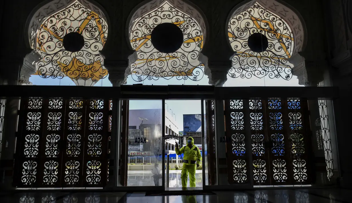 Polisi menyemprotkan cairan disinfektan di Masjid Agung Baiturrahman, Banda Aceh, Indonesia, 20 Maret 2020. Hingga 21 Maret 2020 siang, jumlah pasien positif virus corona COVID-19 di Indonesia telah mencapai 450 orang, 38 meninggal. (Photo by CHAIDEER MAHYUDDIN/AFP)