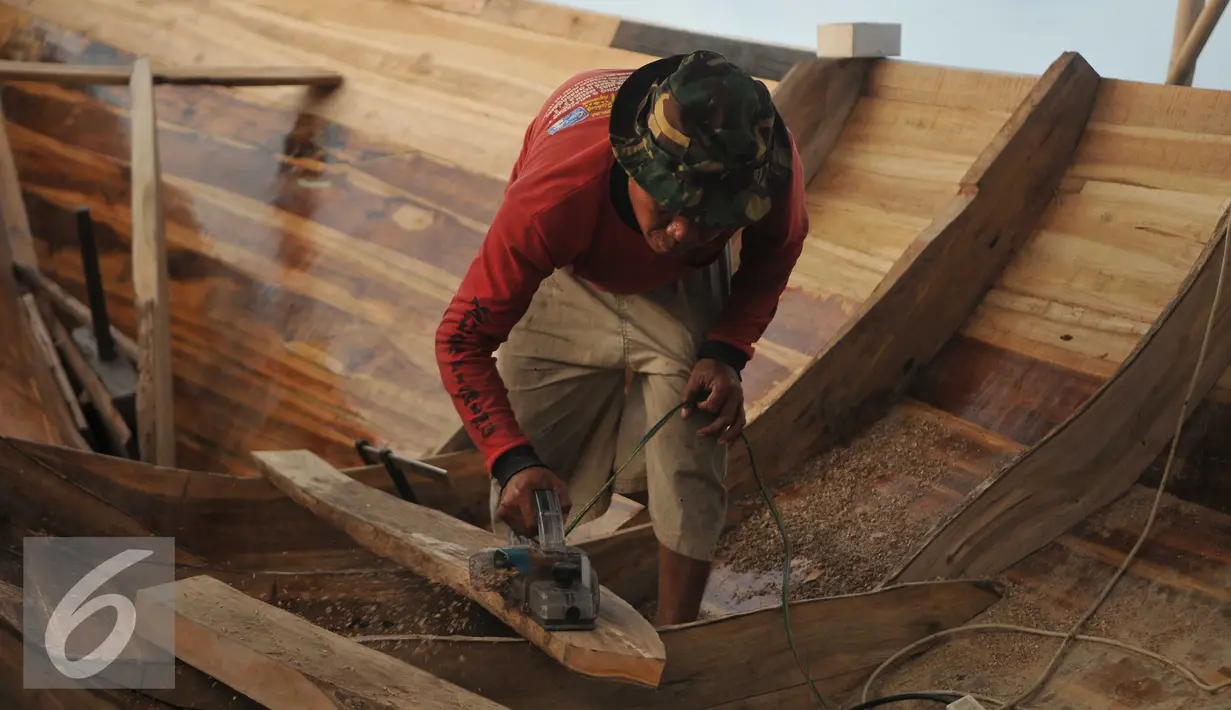 Pekerja menyerut kayu untuk pembuatan kapal kayu berjenis But Tempel di Cilincing, Jakarta, Selasa (9/8). Proses pembuatan kapal kayu tersebut memakan waktu sekitar 2 bulan. (Liputan6.com/Gempur M Surya)