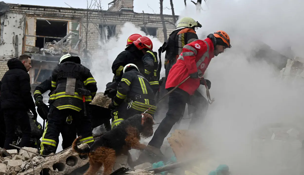 Anggota tim pencarian dan penyelamatan bekerja dengan anjing pelacak di lokasi serangan rudal di Kharkiv pada 23 Januari 2024. (SERGEY BOBOK/AFP)