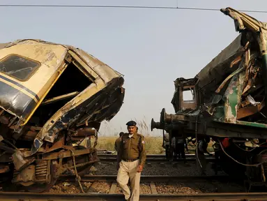 Polisi berjalan diantara gerbong yang rusak parah usai kecelakaan yang melibatkan dua kereta penumpang di Palwal, India, Selasa (8/12). Menurut media setempat, kejadian itu menewaskan satu orang dan puluhan lainnya luka parah. (REUTERS/Anindito Mukherjee)