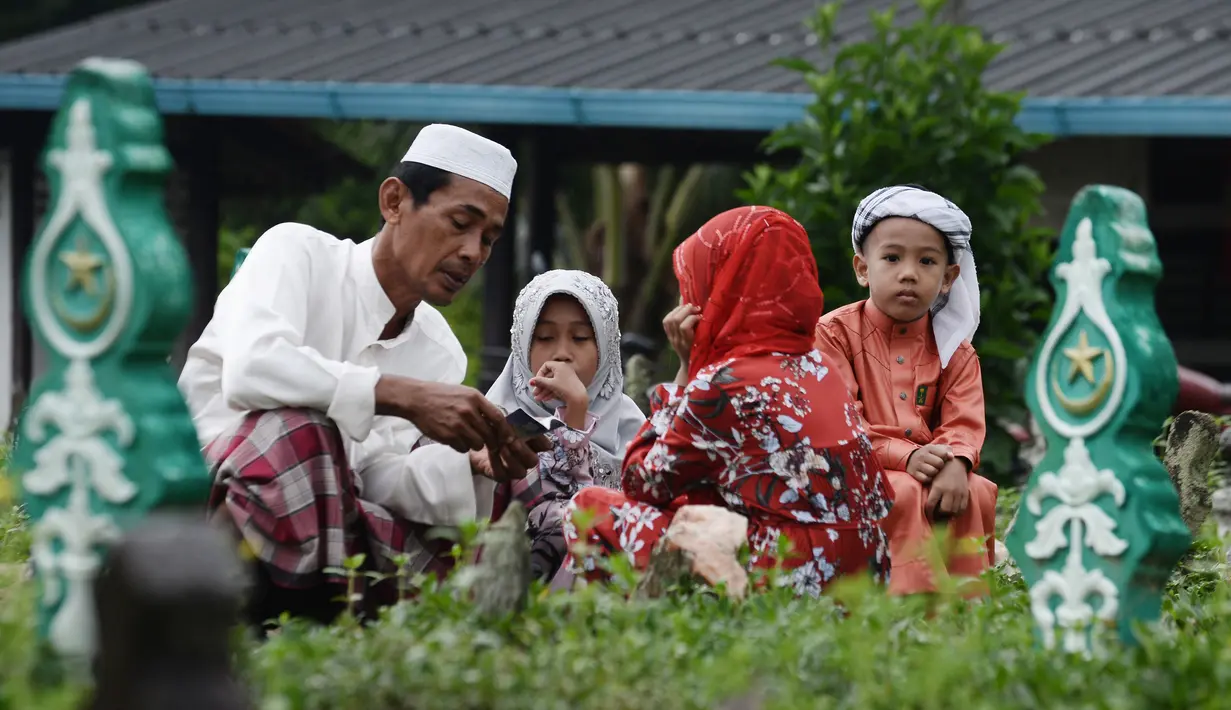Seorang pria memanjatkan doa di makam kerabatnya saat Idul Fitri di Provinsi Narathiwat, Thailand, Rabu (5/6/2019). Tradisi ziarah kubur saat Idul Fitri ini mirip dengan apa yang biasa dilakukan muslim di Indonesia. (MADAREE TOHLALA/AFP)