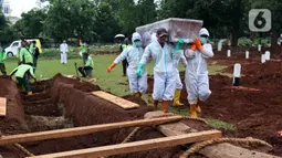 Petugas membawa peti berisi jenazah yang akan dimakamkan dengan protokol COVID-19 di TPU Bambu Apus, Jakarta, Jumat (22/1/2021). Sejak dibuka Kamis (21/1) kemarin hingga hari ini, tercatat sekitar 35 jenazah dimakamkan dengan protokol COVID-19 di TPU Bambu Apus. (Liputan6.com/Helmi Fithriansyah)