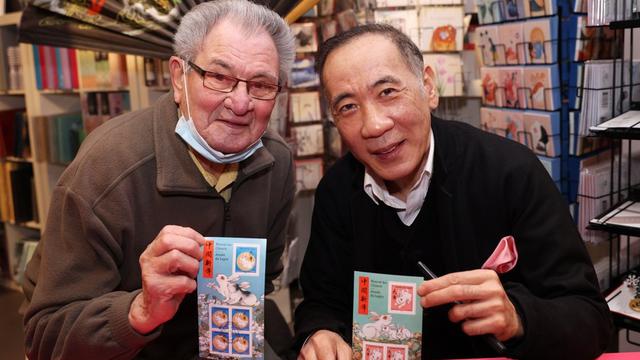 Seorang pelanggan berfoto dengan seniman Tiongkok Chen Jianghong (kanan), perancang prangko peringatan Tahun Kelinci, dalam upacara peluncuran di Paris, Prancis, 14 Januari 2023. (Xinhua/Gao Jing)