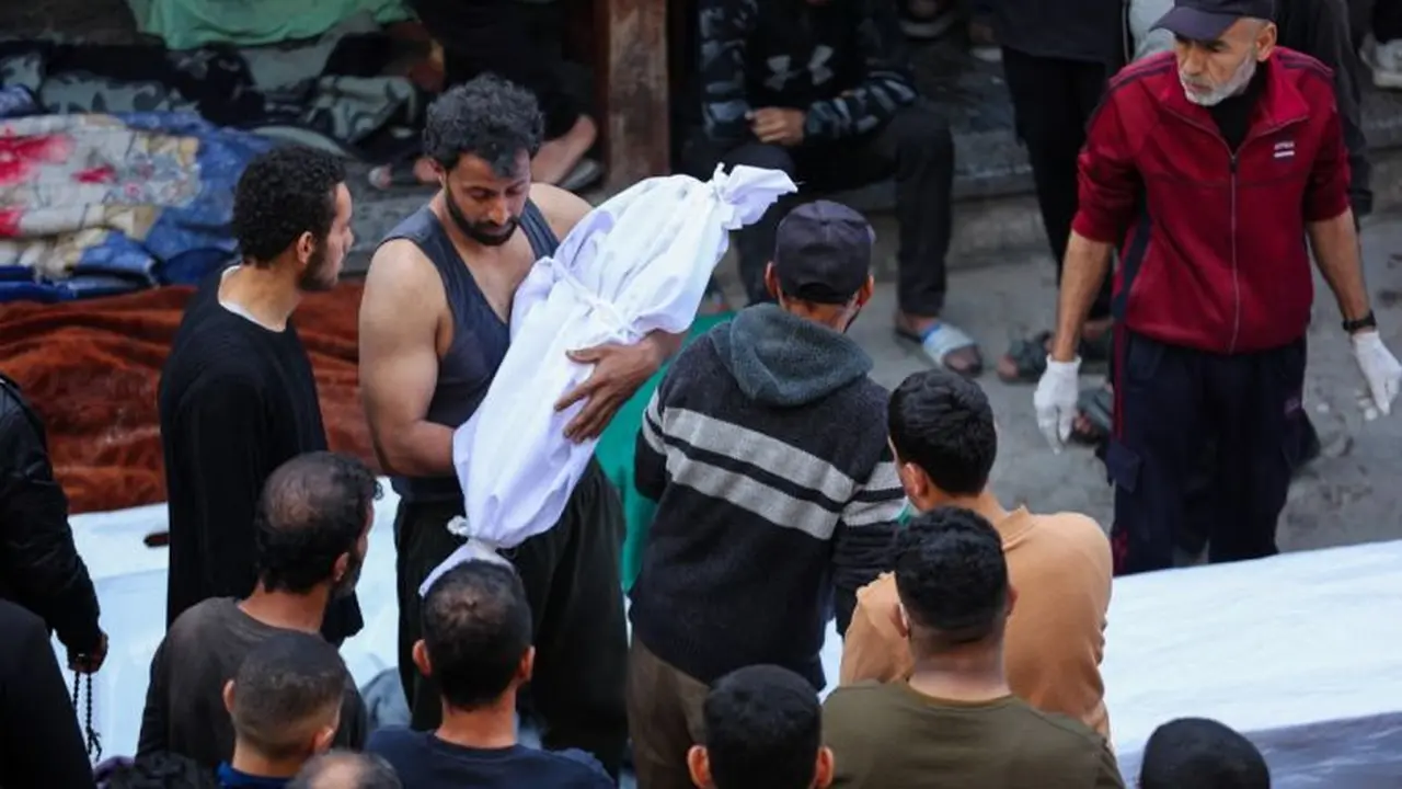 Seorang pria membawa jenazah seorang anak yang terbunuh akibat serangan Israel di Rumah Sakit Al-Mamdani di Kota Gaza (Foto: Omar Al-Qattaa/AFP)