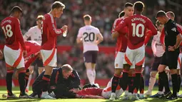 Pemain Manchester United, Matthijs de Ligt mendapatkan perawatan dari tim medis saat kepalanya mengalami pendarahan setelah berbenturan dengan pemain Brentford, Kevin Schade dalam laga lanjutan Liga Inggris 2024/2025 di Old Trafford, Manchester, Sabtu (19/10/2024). (AFP/Oli Scarff)