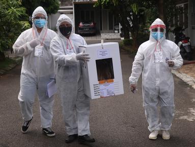 Petugas KPPS dengan mengenakan APD lengkap menuju rumah warga yang sakit untuk memberikan hak pilihnya dalam Pilkada Kota Tangerang Selatan di Paku Jaya, Serpong Utara, Rabu (9/12/2020). Mereka mendatangi warga yang tidak bisa mencoblos di TPS karena sakit. (Liputan6.com/Angga Yuniar)