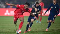 Pemain naturalisasi baru Vietnam, Nguyen Xuan Son (kiri) menggiring bola melewati pemain Thailand, Nicholas Mickelson dalam laga leg pertama final Piala AFF 2024 yang berlangsung di Viet Tri Stadium, Vietnam, Selasa (02/01/2025) waktu setempat. (AFP/Nhac Nguyen)