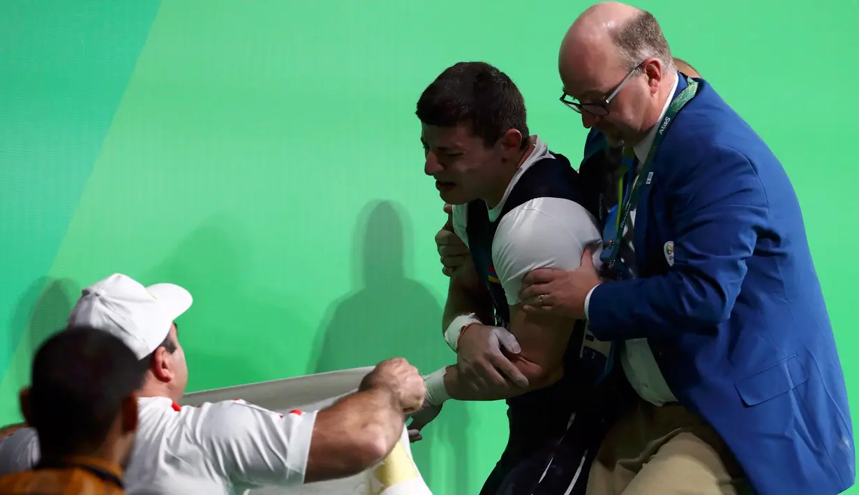 Atlet angkat besi Armenia, Andranik Karapetyan menahan sakit dan menangis usai mengalami cedera horor ketika tampil pada Olimpiade 2016 di Rio de Janeiro, Rabu (10/8). Siku Karapetyan patah saat hendak mengangkat beban 195 kilogram (REUTERS/Yves Herman)