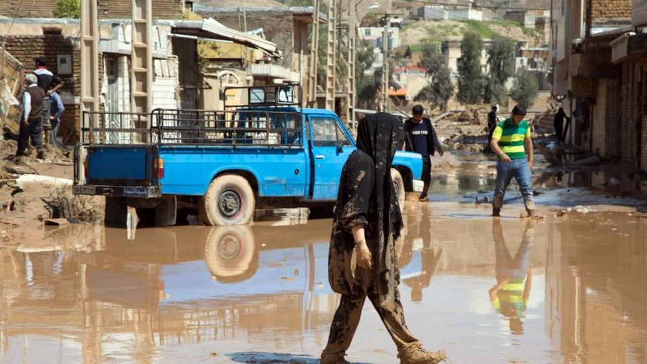 Wanita berjalan di lokasi bekas banjir Iran yang sudah surut di Poldokhtar, Provinsi Lorestan. (AFP)