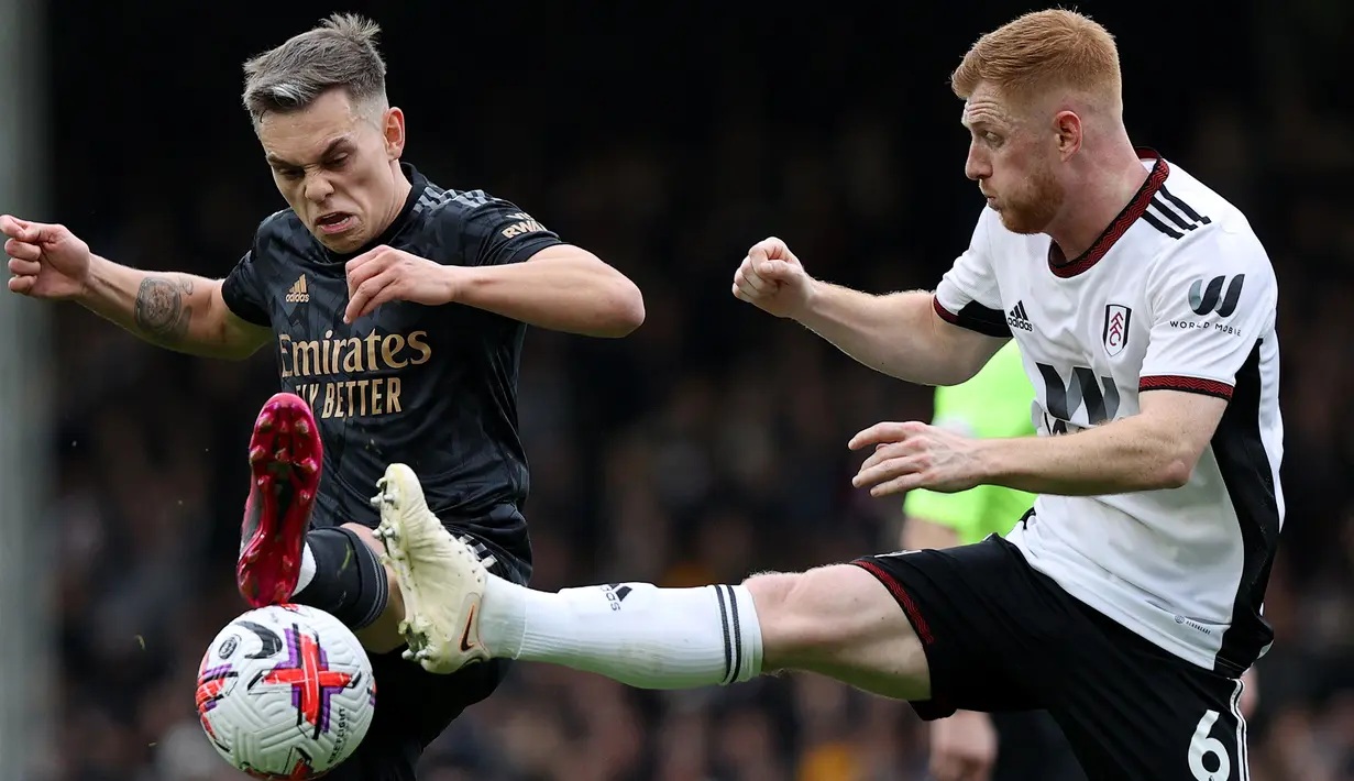 Gelandang Arsenal, Leandro Trossard (kiri) berebut bola dengan gelandang Fulham, Harrison Reed pada laga Liga Inggris 2022/2023 di Craven Cottage, London (12/3/2023). Leandro Trossard yang baru didatangkan Arsenal pada bursa transfer Januari 2023 menjadi pemain kedua yang mencetak hattrick assist di Liga Inggris pada musim 2022/2023. Ia melakukannya di pekan ke-27 saat Arsenal menang 3-0 atas Fulham. (AFP/Adrian Dennis)