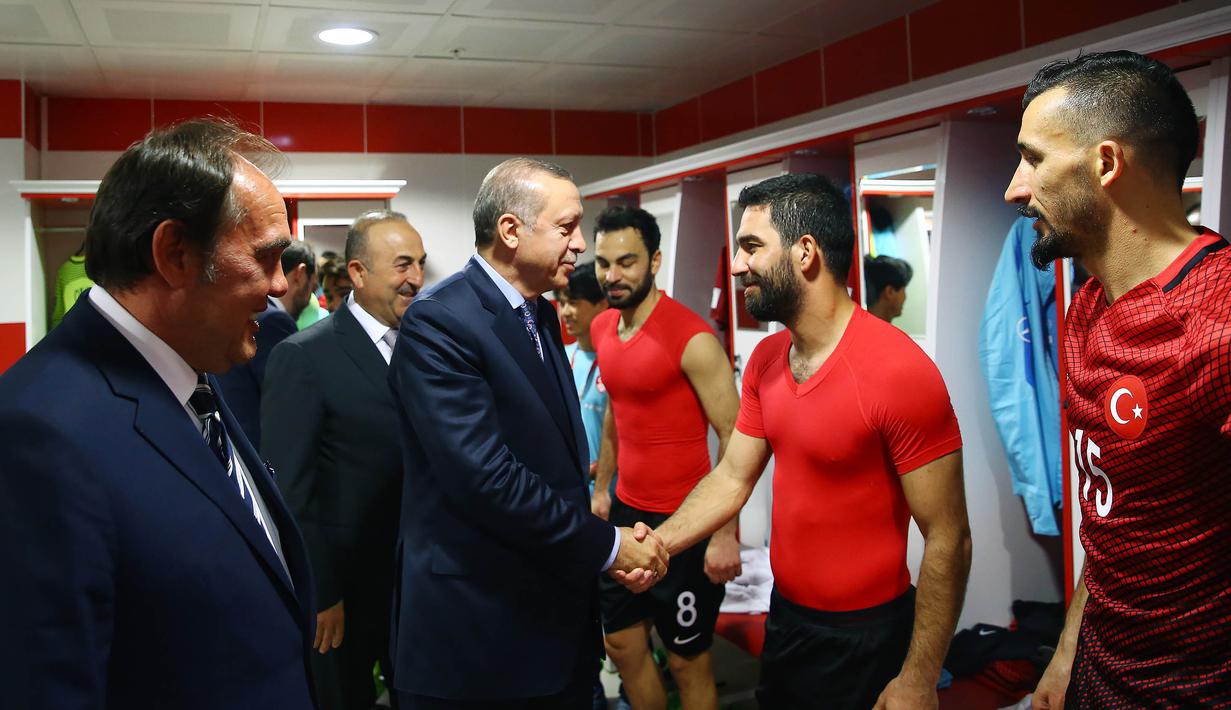 Presiden Turki, Tayyip Erdogan, masuk ke ruang ganti menyalami gelandang Timnas Turki, Arda Turan, jelang laga kualifikasi Piala Dunia melawan Finlandia di Stadion Antalya, Turki, Jumat (24/3/2017). Turki menang 2-0 atas Finlandia. (AFP/Kayhan Ozer)