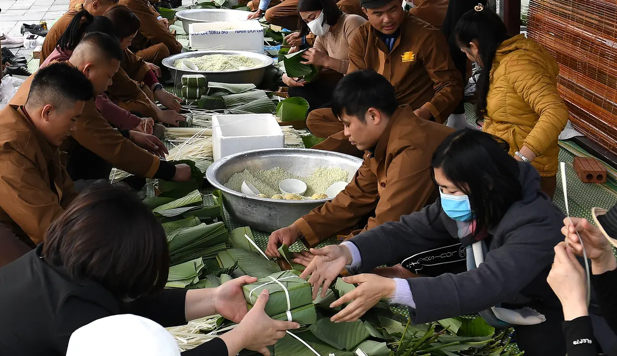 Orang-orang menyiapkan "Banh Chung" atau kue beras tradisional Vietnam untuk amal, menjelang Tahun Baru Imlek atau festival Tet di Pagoda Tam Chuc di provinsi Ha Nam (7/1/2023). Banh Chung adalah kelezatan khas Vietnam yang terbuat dari ketan, daging babi, dan kacang hijau yang dibungkus dengan daun pisang dan dimasak selama 10 jam. (AFP/Nhac Nguyen)