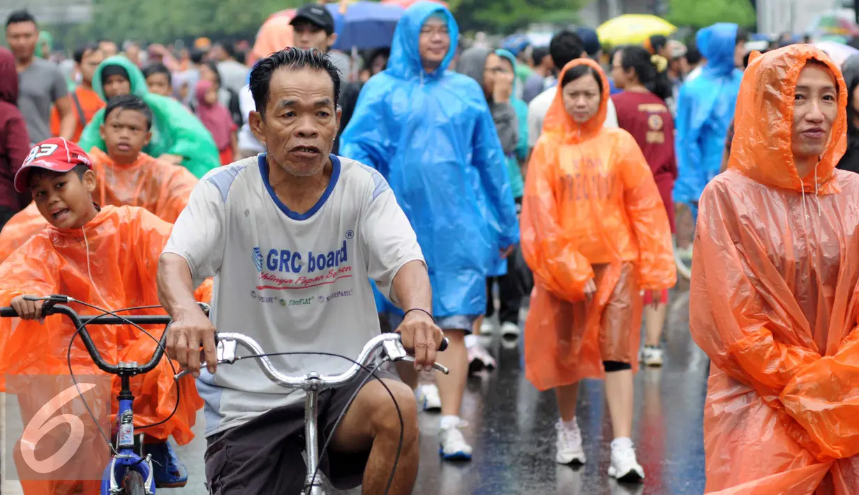 Sejumlah warga mengenakan jas hujan saat mengikuti kegiatan Car Free Day, Jakarta, Minggu (24/1/2016). Meski hujan mengguyur Ibu Kota sejak semalam, kegiatan CFD pagi di kawasan Bundaran Hotel Indonesia masih tetap ramai. (Liputan6.com/Helmi Affandi)