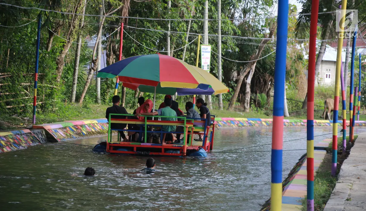 Wisatawan menaiki perahu apung di Wisata Air Toino, Desa Talulobutu, Kecamatan Tapa, Kabupaten Bone Bolango, Gorontalo, Sabtu (30/3). Wisatawan yang datang mulai dari anak-anak, muda-mudi hingga orang tua. (Liputan6.com/Arfandi Ibrahim)