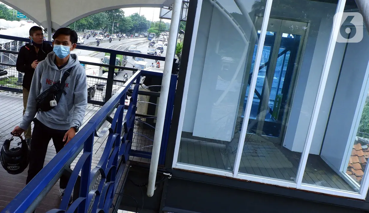 Pejalan kaki melintas di dekat lift JPO yang terbengkalai di Jalan Jembatan Gantung, Daan Mogot, Jakarta Barat, Rabu (17/3/2021).  JPO yang pernah rusak dan telah selesai diperbaiki ini mempunyai gaya artistik yang sangat  bagus dengan fasilitas yang cukup banyak. (Liputan6.com/Johan Tallo)