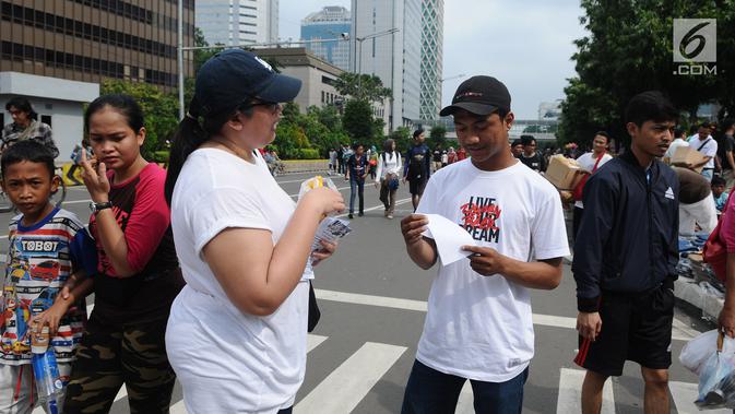 Komunitas Sahabat Thamrin membagi selebaran ke warga di kawasan Thamrin, Jakarta, Minggu (13/1). Sahabat Thamrin mengenang tragedi 3 tahun bom Thamrin bertema 'Menerima Perbedaan untuk Merayakan Kebersamaan dan Perdamaian'. (Liputan6.com/Herman Zakharia)