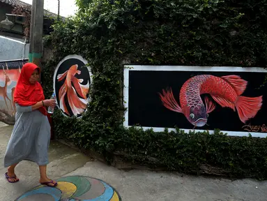 Warga berjalan dekat mural yang menghiasi tembok rumah warga RT 02/RW 07 Kampung Warna-warni, Kelurahan Pengadegan, Jakarta Selatan, Selasa (10/12/2019). Mural di kampung ini dibuat dari dana swadaya warga setempat. (merdeka.com/Imam Buhori)