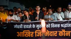 Anggota Kongres Pemuda India ikut serta dalam pawai menyalakan lilin di New Delhi, India, Senin (31/10/2022). Lilin dinyalakan sebagai bentuk penghormatan kepada para korban yang meninggal setelah tragedi jembatan ambruk di seberang Sungai Machchhu. (AFP/Sajjad HUSSAIN)