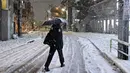 Seorang wanita berjalan di jalan yang tertutup salju di Distrik Nerima, Tokyo pada tanggal 5 Februari 2024. Hujan salju mencapai puncaknya pada Senin malam. (Kazuhiro NOGI/AFP)