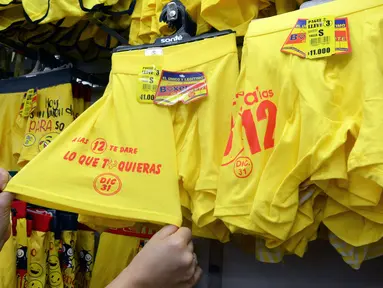 Calon pembeli melihat pakaian dalam berwarna kuning yang dijualnya di sebuah toko di Medellin, Kolombia, Kamis (29/12). Menyambut perayaan tahun baru, celana dalam berwarna kuning banyak diburu warga Kolombia. (AFP PHOTO/Camilo GIL)