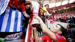 Jose Antonio Reyes memamerkan trofi juara Liga Europa 2015 ke para pendukung setia Sevilla di Stadion Narodowy, Polandia, Kamis (28/5/2015). Sevilla memecahkan rekor meraih trofi Liga Europa terbanyak, yakni empat gelar. (Reuters/Carl Recine)