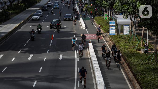 Sejumlah pesepeda melintasi jalur kendaraan bermotor saat uji coba pembatas jalur sepeda permanen di kawasan Sudirman, Jakarta, Minggu (28/2/2021). Uji coba berlangsung selama tahap penyempurnaan jalur sepeda permanen yang ditargetkan rampung akhir Maret 2021. (Liputan6.com/Johan Tallo)