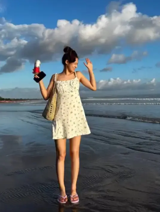 Seolhyun juga libur di Bali, saat di pantai ia mengenakan mini dress putih bercorak spaghetti strap. Ia tampil santai dengan sandal ungu dan tote bag coklat. [@s2seolhyuns2]