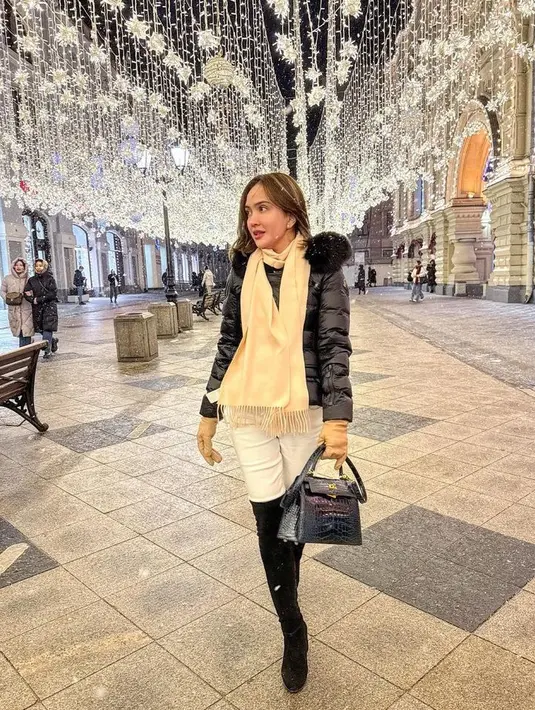 Di bawah salju, Shandy mengenakan padding jaket hitam dan syal beige, celana putih dan boots hitamnya. [@shandyaulia]