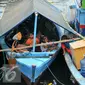 Sejumlah anak penghuni pasar ikan Penjaringan berada di atas perahu saat rumahnya mulai dihancurkan oleh alat berat petugas, Jakarta, Senin (11/4). Pemprov DKI membongkar ratusan rumah di wilayah Pasar Ikan. (Liputan6.com/Yoppy Renato)