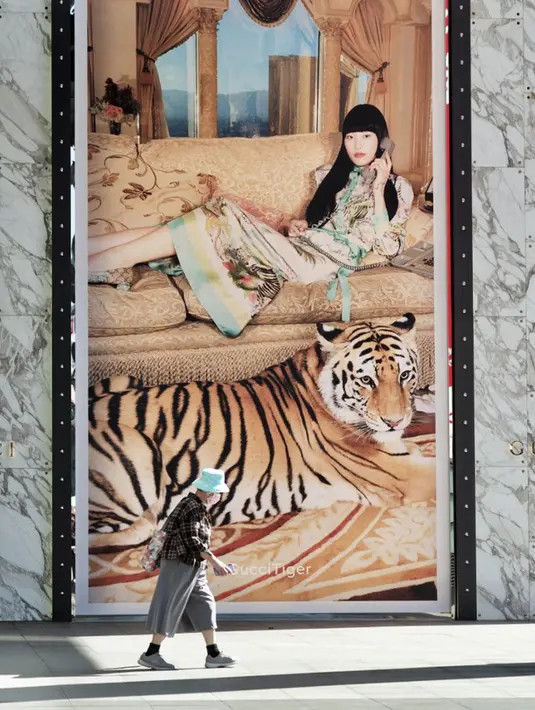Seorang wanita berjalan melewati iklan yang menampilkan macan di depan pusat perbelanjaan jelang Tahun Baru Imlek di Taipei, Taiwan, Kamis (27/1/2022). Tahun Baru Imlek 2022 yang jatuh pada 1 Februari mendatang akan jadi tahun shio macan. (Sam Yeh/AFP)