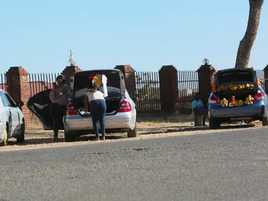 Orang-orang menjual berbagai barang di dalam bagasi mobil di sisi jalan yang sibuk di Harare, 1 Juli 2020. Mobil menjadi pasar bergerak di mana penduduk Zimbabwe menjual barang dagangan dari kendaraan untuk mengatasi kesulitan ekonomi yang disebabkan Covid-19. (AP Photo/Tsvangirayi Mukwazhi)