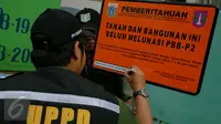 Petugas menulis keterangan pada plang di depan PT DKB Dok Perkapalan Galangan I, Tanjung Priok, Jakarta, Senin (23/11). Langkah ini sebagai peringatan bagi para wajib pajak (WP) kelas menengah ke atas mencapai ratusan miliar (Liputan6.com/Faizal Fanani)