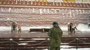Para pekerja membersihkan salju dari Makam Prajurit Tak Dikenal yang dijaga sejumlah prajurit di Tembok Kremlin, Moskow, Rusia, 7 Februari 2022. (AP Photo/Thibault Camus)