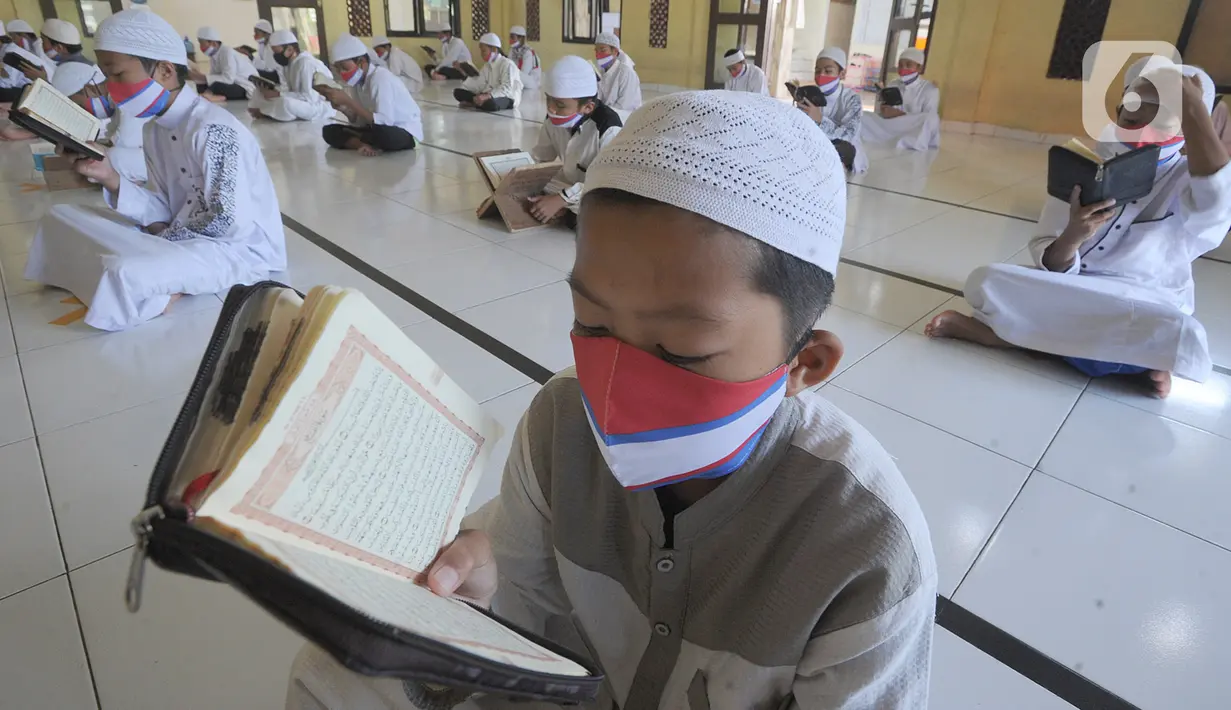 Santri berusia belasan tahun membaca Al quran atau tadarus bersama-sama dengan menerapkan jaga jarak di Masjid Daarul Qu'ran Pesantren Al Kautsar, Cibinong, Bogor, Kamis (7/5/2020). Kegiatan Khatam Al quran tersebut dilakukan rutin di setiap bulan Ramadan. (merdeka.com/Arie Basuki)